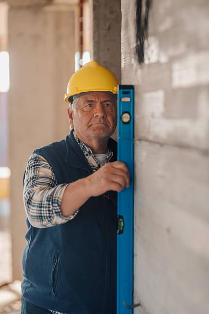 istock Senior construction worker using spirit level on wall in unfinished building 2210538585