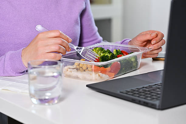 istock Woman having lunch from plastic box in front of laptop 2210549918