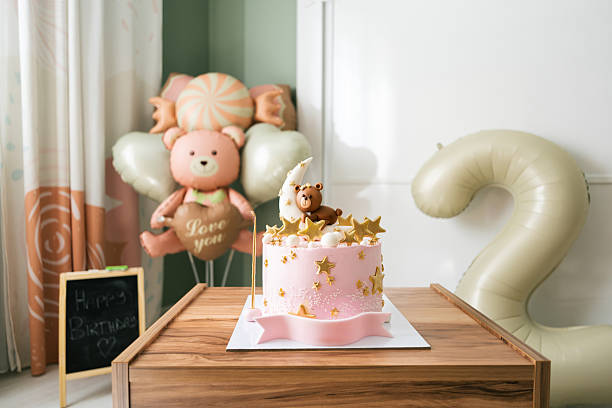 Pink birthday cake decorated with a teddy bear, moon, and stars, celebrating a second birthday