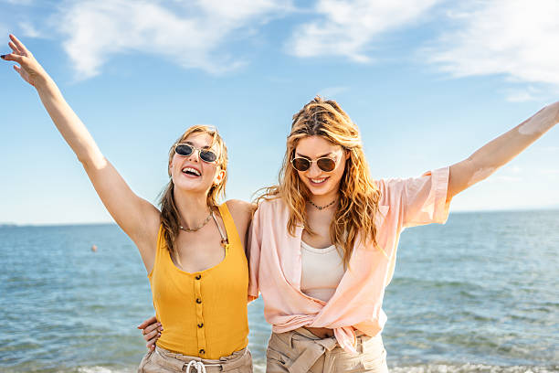 Portrait of a two female friends embracing on the Alcudia beach in Palma de Mallorca in Spain.