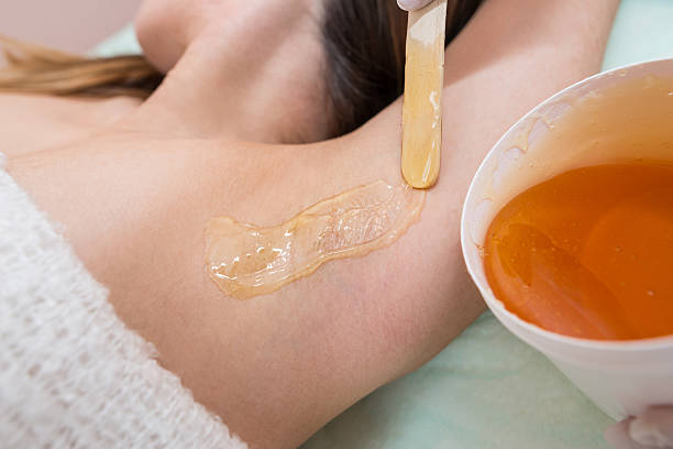 istock Depilation and epilation female armpit with liquid sugar paste by spatula. Hand of cosmetologist applying wax paste on armpit. Smooth underarm concept 2210567155