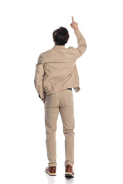 behind view of casual guy pointing finger to the sky while stepping