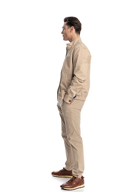 istock side view of cool young guy in beige jacket holding hands in pockets 2210568072