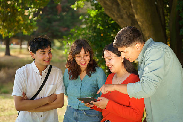 istock Group of students sharing a digital tablet in the park 2210571157