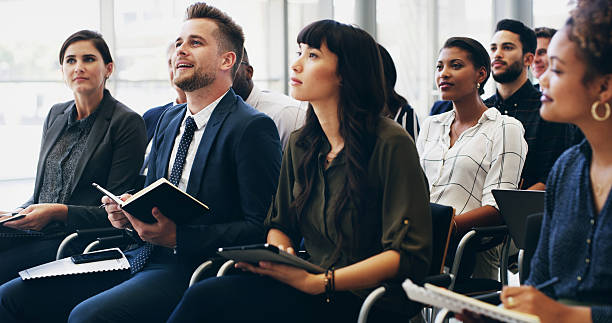 istock Notes, group and business people at seminar with attention for corporate training, development or teamwork. Audience, men and women at conference for presentation, planning and opportunity for growth 2210571278