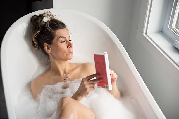 istock Woman relaxing in hot bath reading a book. 2210573182