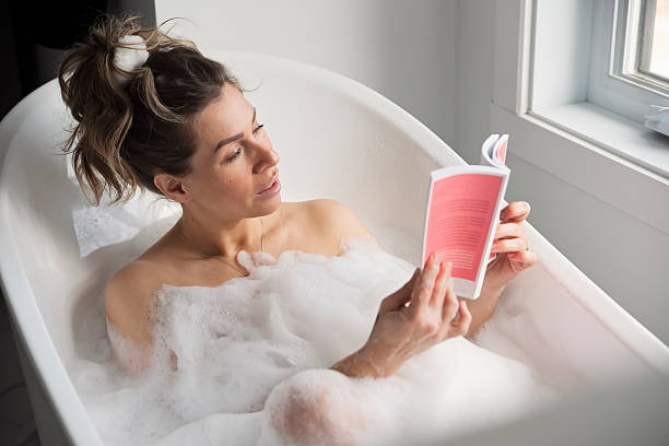 istock Woman relaxing in hot bath reading a book. 2210573212