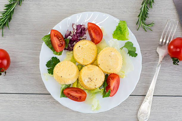 Round omelette with tomatoes and fresh lettuce on a served table.