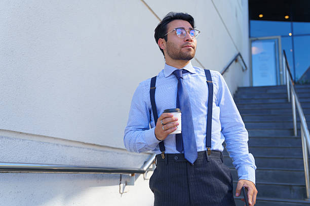 Businessman holding coffee outside office building looking away