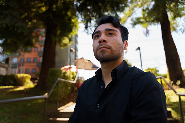 istock Young latino man sitting and thinking outdoors in a park 2210574902