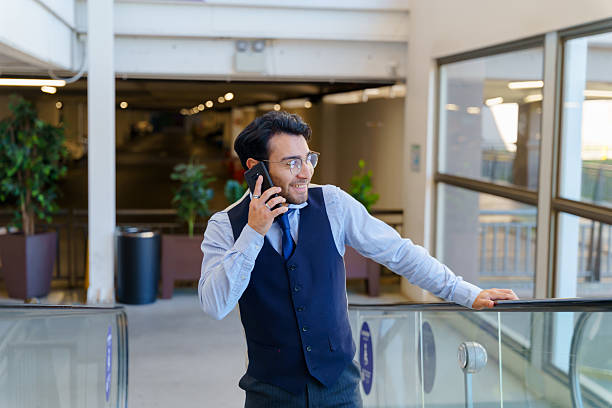 istock Businessman talking on phone while riding on moving walkway in airport 2210574920