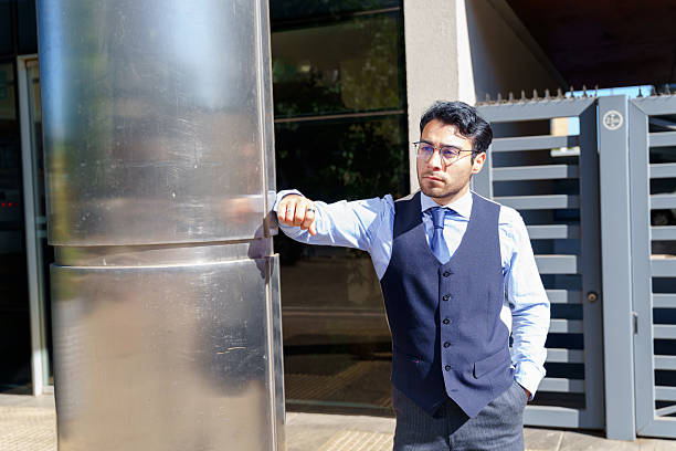 istock Businessman leaning on a pole outside office building 2210575125