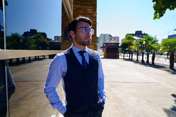 Sophisticated elderly man with a bow tie and vest, posing confidently against a light neutral background in a formal setting.