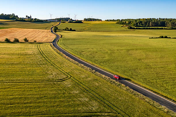 istock Red car driving on rural road 2210575967