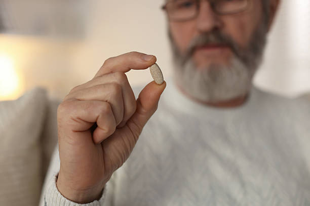 istock Senior man with pill at home, closeup 2210578383