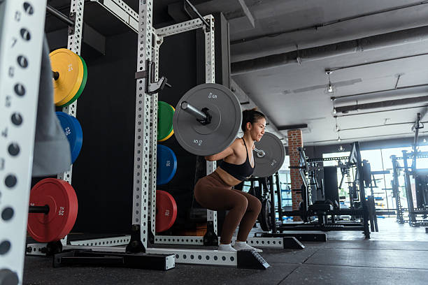 istock Woman performing barbell squat in modern gym during daytime workout session 2210579636