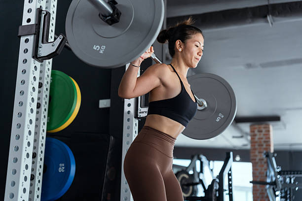 istock Woman performing barbell squat in modern gym during daytime workout session 2210579639