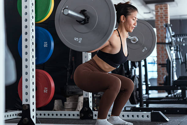 istock Woman performing barbell squat in modern gym during daytime workout session 2210579650