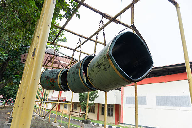 A set of green tunnel tubes hangs from a metal structure in a park like setting Perfect for recreation or outdoor themed projects.
