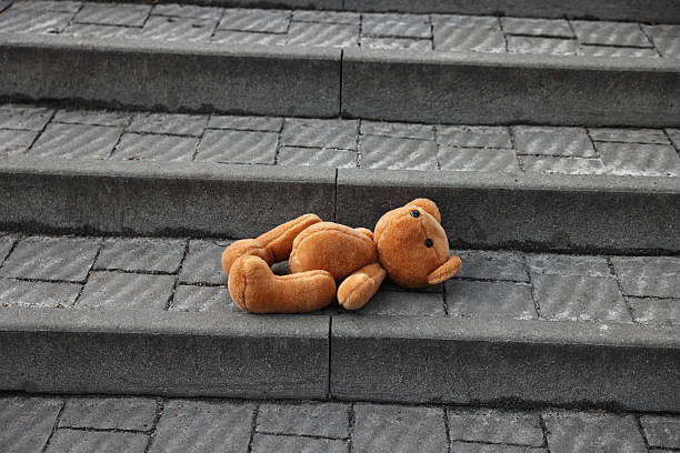 istock Lost brown teddy bear on stairs outdoors 2210583063