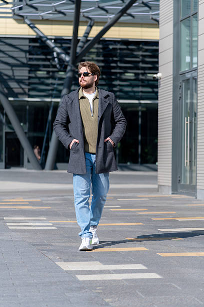 istock Stylish man walks confidently in urban setting during sunny daytime 2210584557