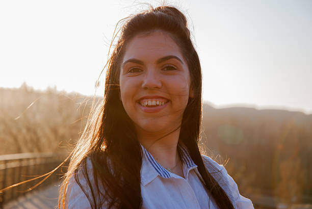 istock Joyful young woman smiling outdoors at sunset 2210585825
