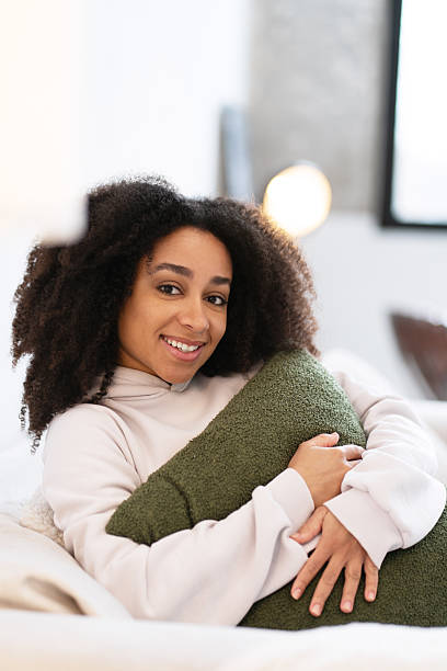 istock Young woman hugging pillow relaxing on bed at home 2210587279