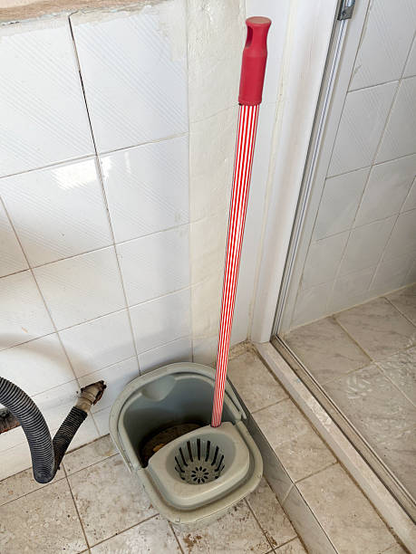 Cleaning mop and bucket on the dirty tiled floor. Cleaning equipment in dirty bathroom or toilet