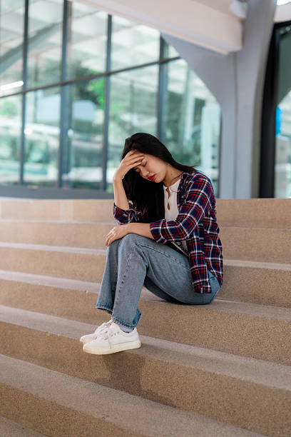 istock Sad student sitting on stairs with head in hand 2210590908