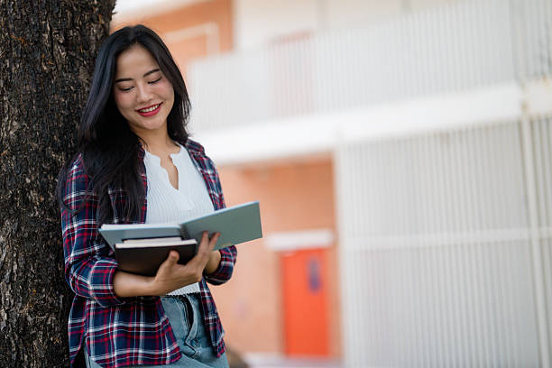 istock Happy student reading a book in the campus park 2210591074