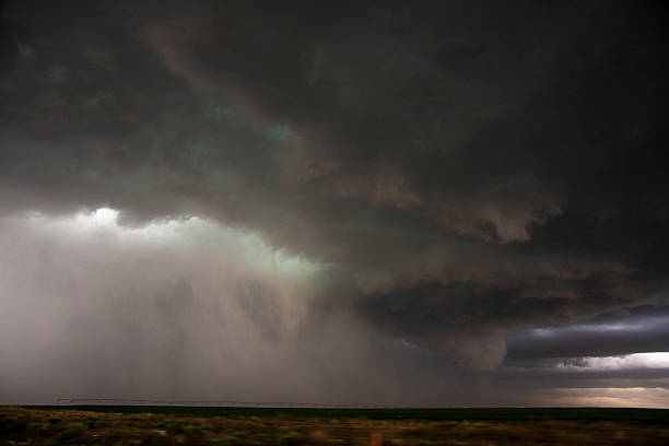 Here comes the rain! Heavy, dark, illuminated stormy sky over a west Texas field with visible rain in the distance.