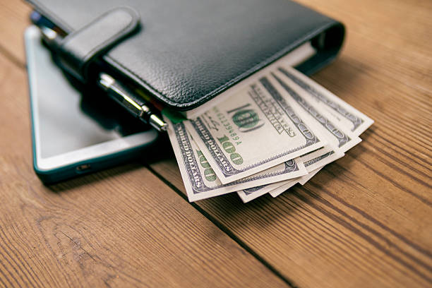 istock Neatly placed US dollar bills with phone and planner. 2210592906