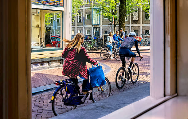 Amsterdam, Netherlands - 09-18-2024: People riding bikes through streets of Amsterdam