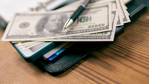 istock Hundred-dollar bills and a pen lay on an open planner. 2210592945