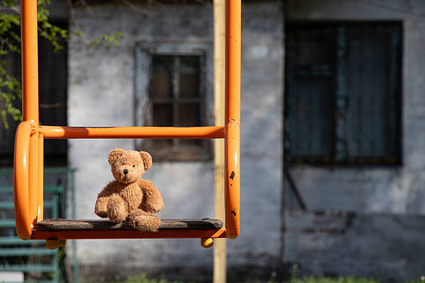 Lonely teddy bear on old bed near green wall outdoors