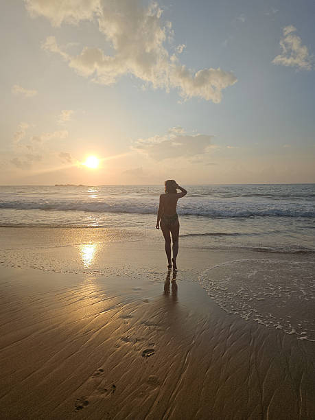 istock Woman walking on the beach at sunrise 2210604318
