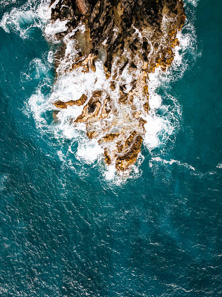 Waves crash into a dark volcanic rock studded coastline in Kona area on the Big Island of Hawaii.  The beautiful raw views of Pacific Hawaiian islands.