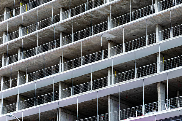 Elevated perspective of a construction site featuring workers on various floors, showcasing the structural development of an apartment building.