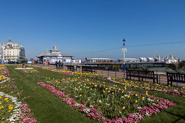 View of ornate gardens in the centre of Eastbourne, UK.  People can be seen on the promenade