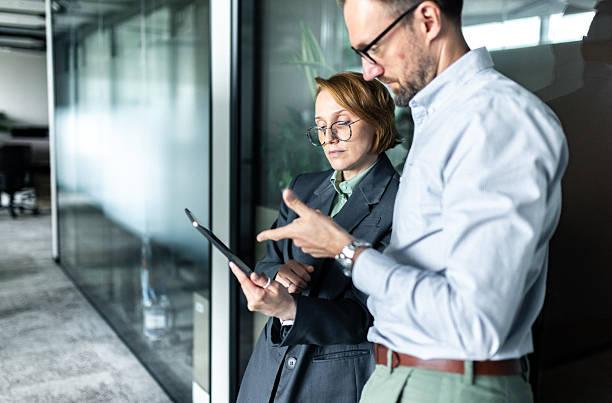 istock Two Business Professionals Discussing Information on a Tablet in a Modern Office 2210605670