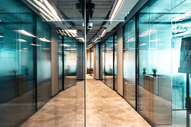 Modern office corridor with glass partitions and professional lighting