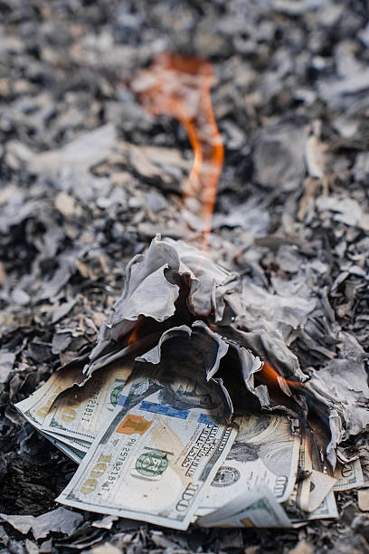 istock Burning US Dollar Bills on Ashes Representing Financial Loss and Waste 2210606960