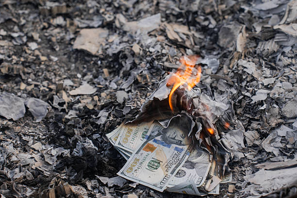 istock Burning US Dollar Bills on Ashes Representing Financial Loss and Waste 2210607047