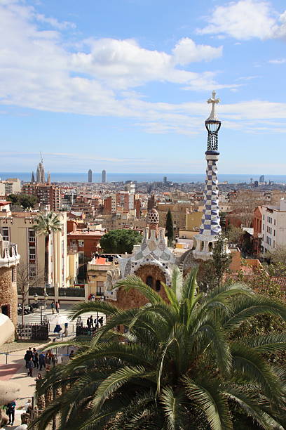 Barcelona, Spain - June 16, 2013: Lovely summer day in Park Guell (Gaudi park, Barcelona). Tourists walking in the park gardens. Clear sky with light clouds on the background. 