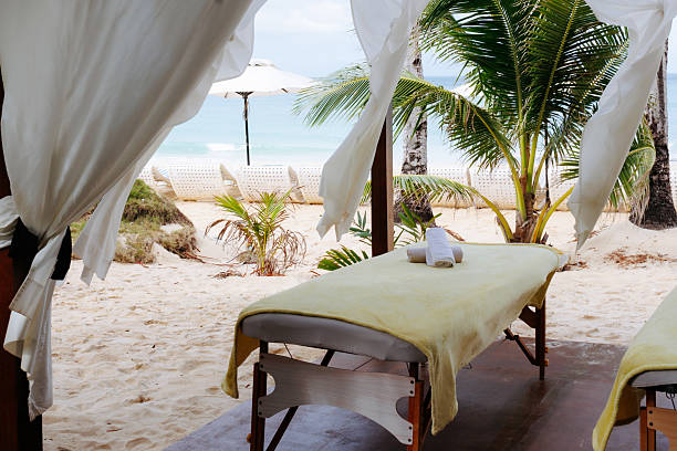 Two women in spa robes unwind in a serene pool area, enjoying a peaceful moment. They recline on chairs next to a refreshing drink, encapsulating relaxation and leisure in a tranquil indoor setting.