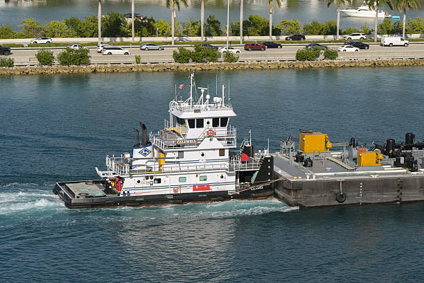 Miami, Florida, USA - 4 January 2025: Tug boat Caldwell pushing a heavy industrial tanker barge n the Port of Miami.