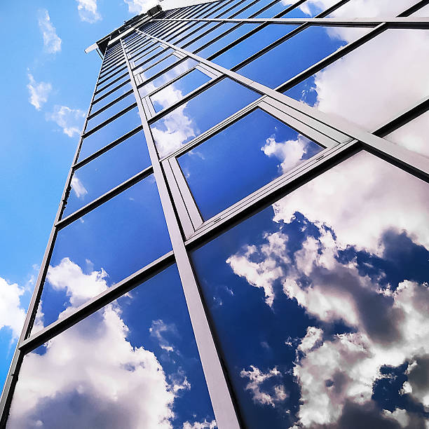A reflection of the blue sky in the window outside. Skyscraper view from below. Buildings in the city and sky