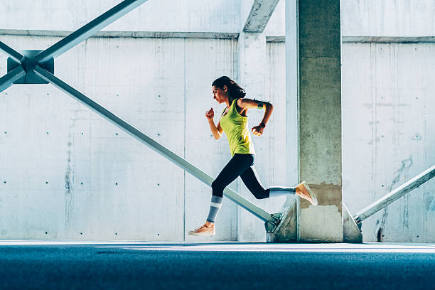 Woman sprinting against concrete backdrop