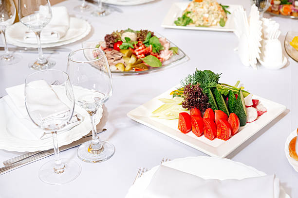 Colorful assortment of sliced raw vegetables including tomatoes, cucumbers, radishes, and greens arranged on a white banquet plate.