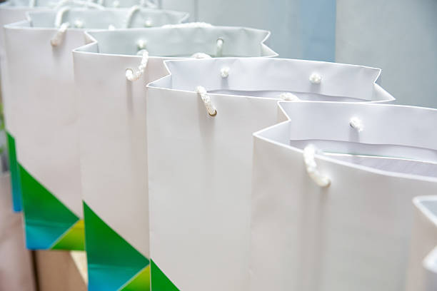 A row of white gift bags with green and blue accents, prepared for a corporate event, party, or promotional giveaway.